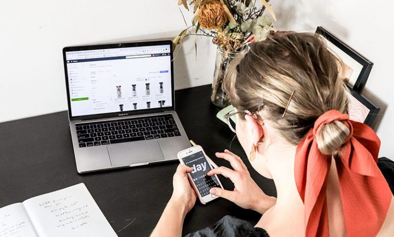 Mujer revisando en su celular y notebook como integrarse con Perfit email marketing